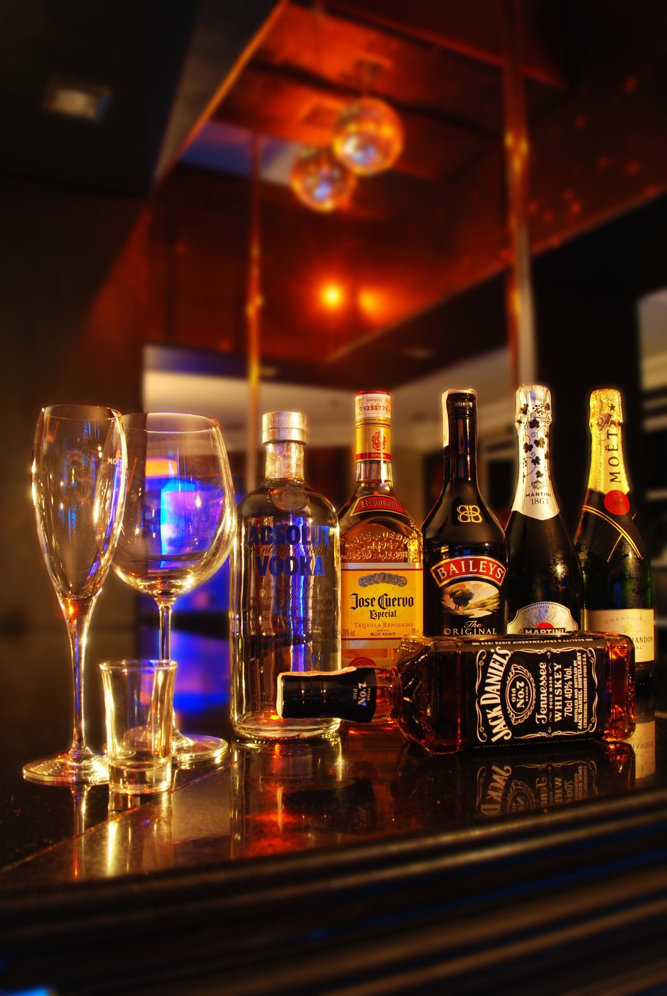 Una barra con varias botellas de licor y dos vasos vacíos.