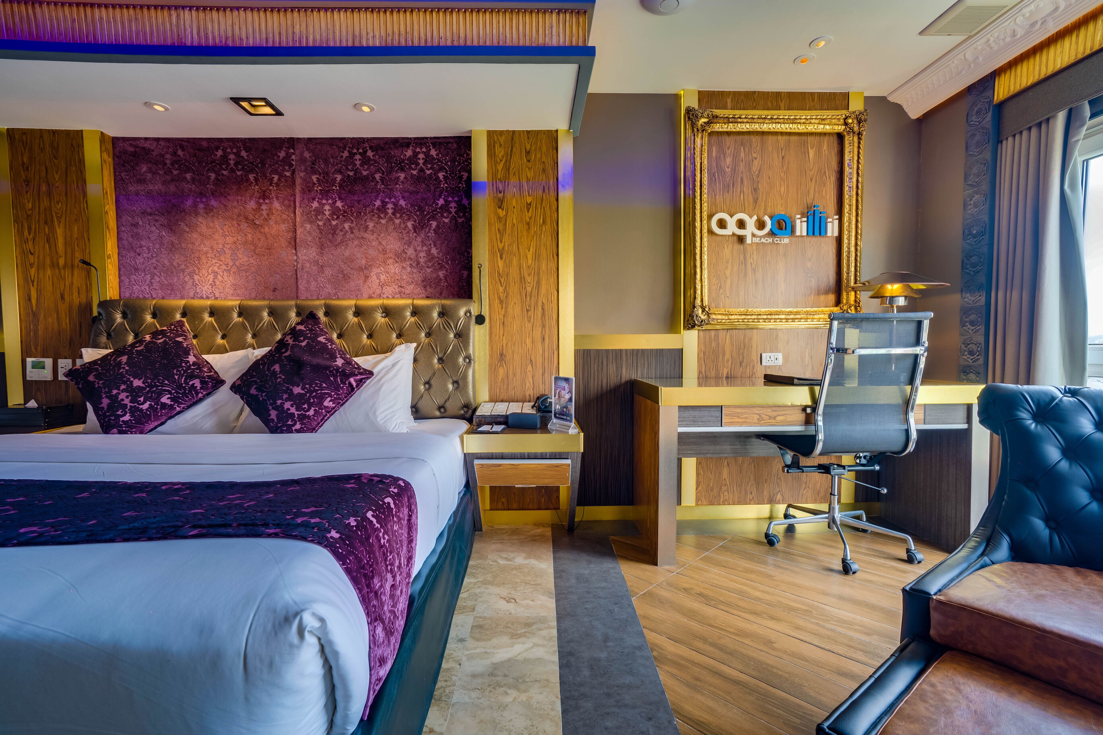 A hotel room with a large bed, a desk, a chair, and a mirror.