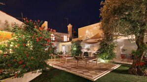 A courtyard with a checkered floor, outdoor seating, and a tree with red flowers. - Casa do Terreiro do Poço (Borba)