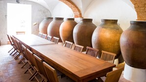 A long wooden table with chairs, large vases, and a brick wall with a curved ceiling. - Casa do Terreiro do Poço (Borba)