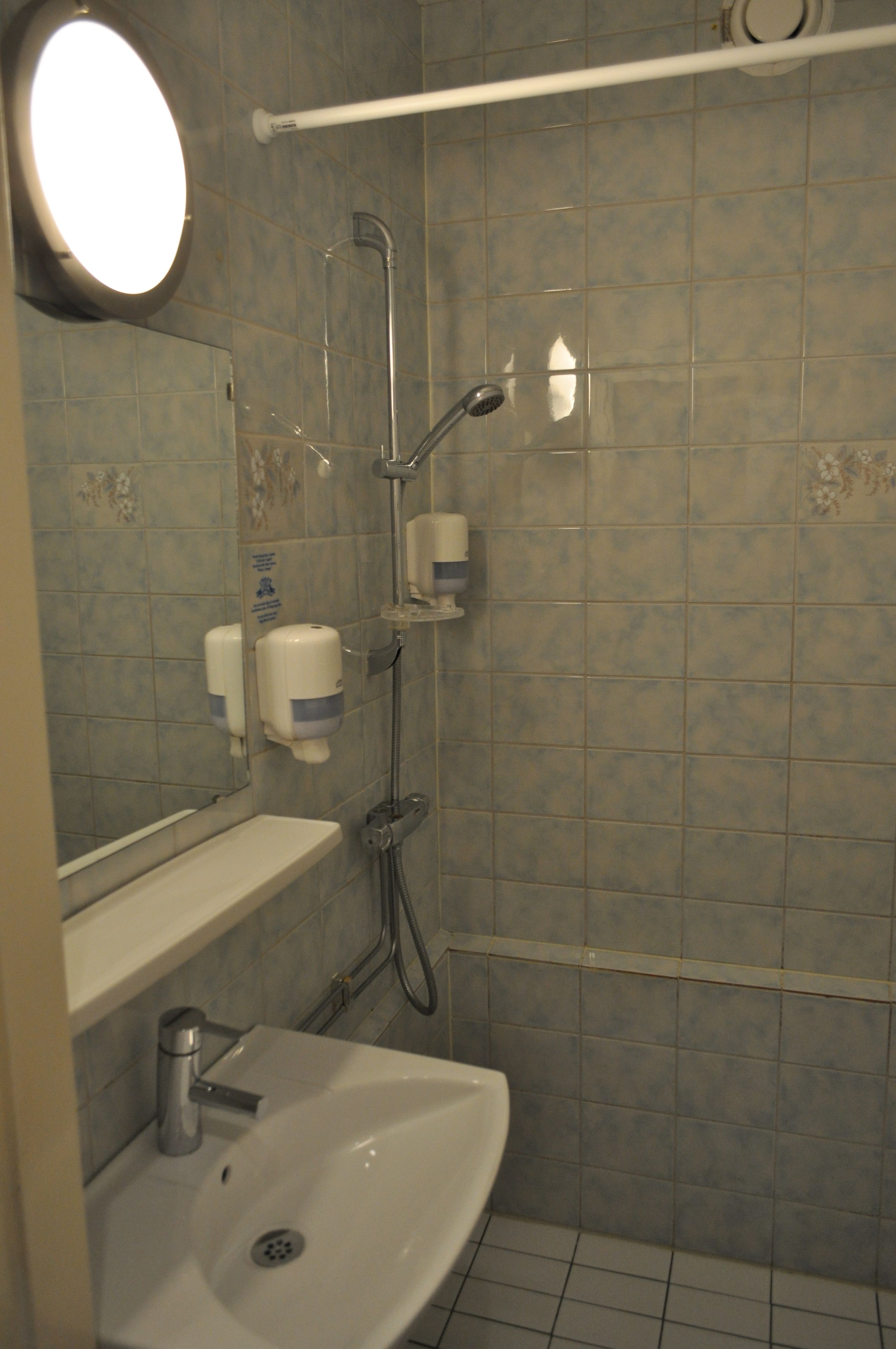 A bathroom with a sink, mirror, and shower.
