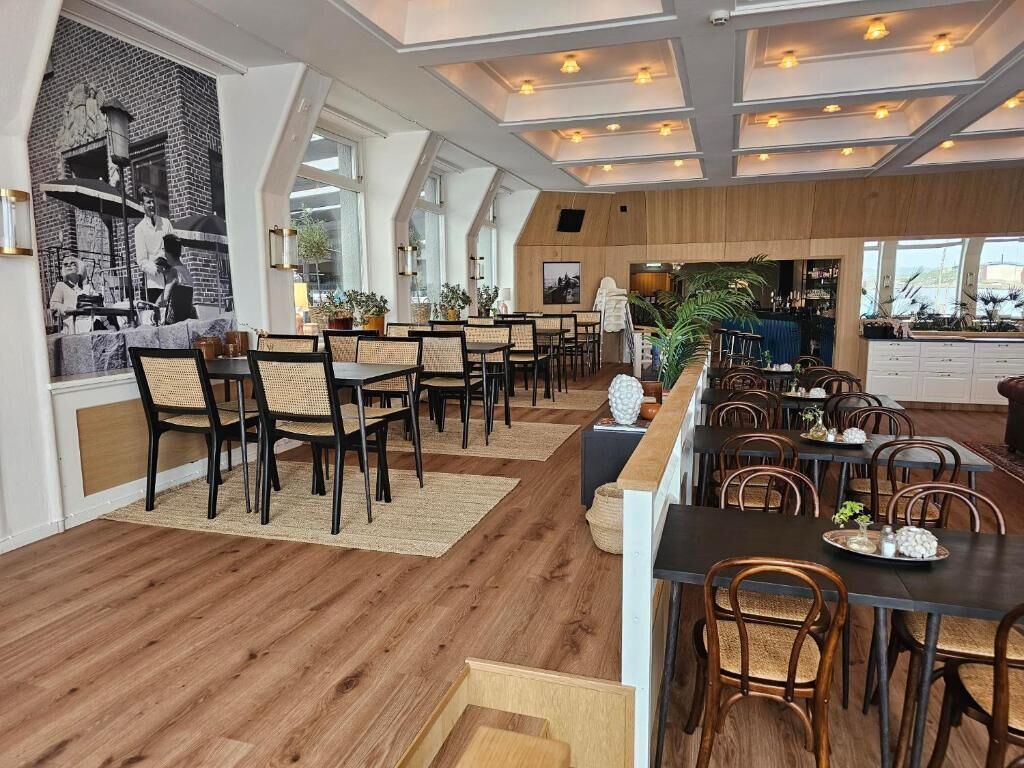 A restaurant with high ceilings, exposed beams, and a mix of wooden and upholstered seating.