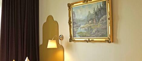 Una habitación de hotel con dos camas, un cuadro en la pared, una lámpara y una ventana con cortinas.