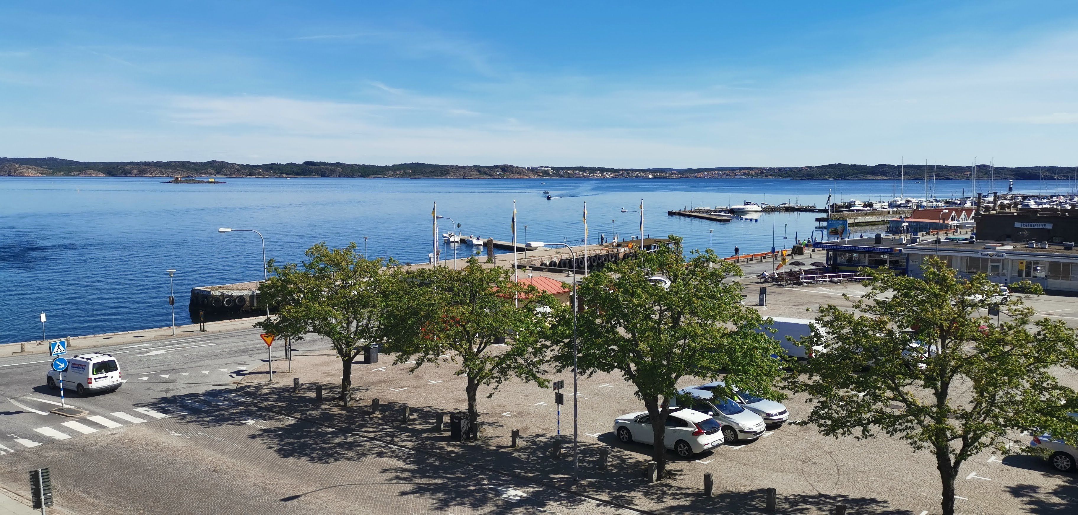 A marina with boats docked, a parking area with cars, and a clear view of the water.