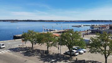 A marina with boats docked, a parking area with cars, and a clear view of the water.