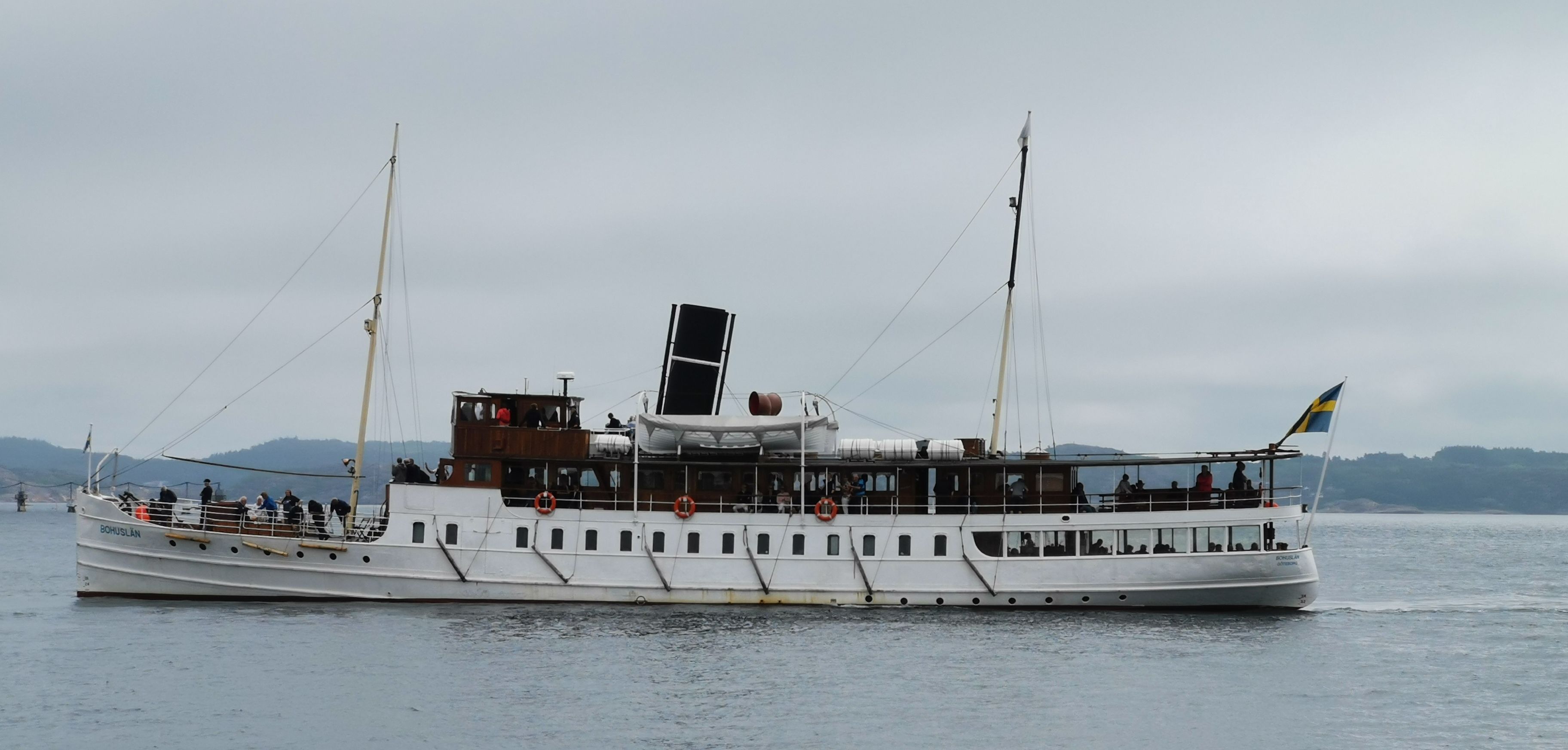 Ett stort, vitt kryssningsfartyg som trafikerar floder, med flera däck och många passagerare.