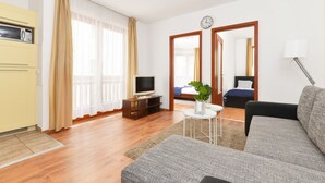 Ett modernt vardagsrum med en soffa, en tv, ett litet bord med en växt och en spegel.