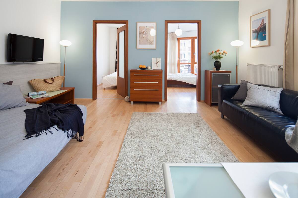 A modern bedroom with a bed, bedside table, lamp, and a view to a balcony.