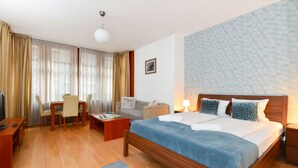 Ett hotellrum med en stor säng, ett skrivbord med en stol, en soffa och en tv.