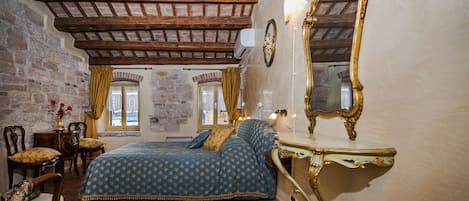 Un dormitorio con cama, espejo, cómoda y pared de piedra.