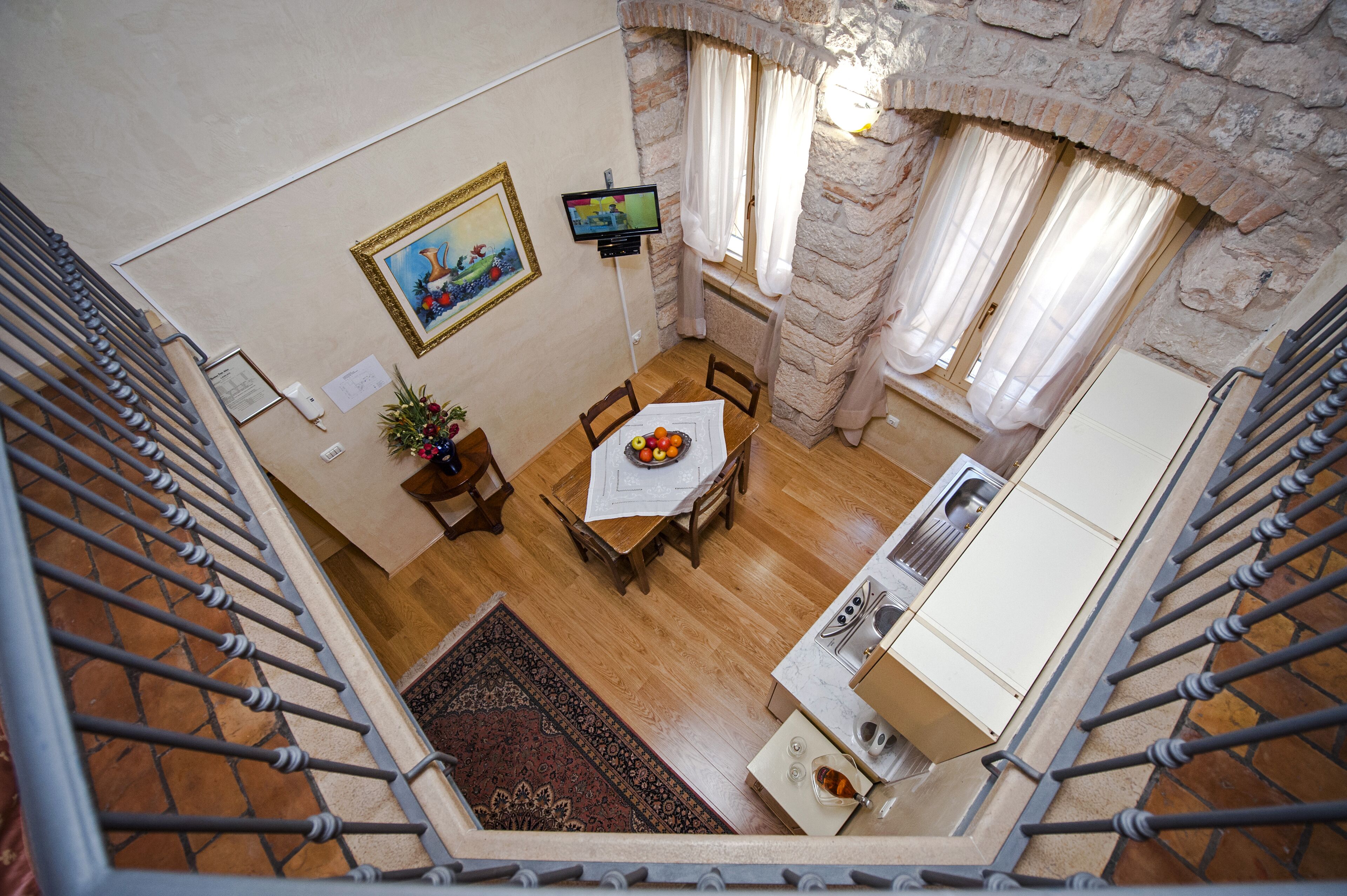 A dining area with a table set for two, a painting on the wall, and a kitchen area with a stove and sink.