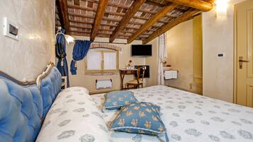 Ein Schlafzimmer mit Holzboden, einem Bett mit floralem Bettzeug, einem Fernseher und einem kleinen Tisch mit Stuhl.