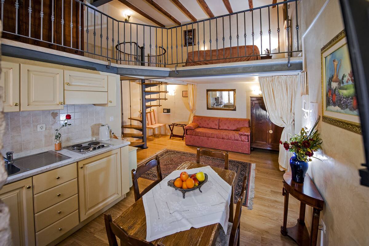 Una cocina amplia con zona de comedor, pisos de madera y una escalera que conduce a un nivel superior.