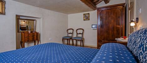 Une chambre à coucher avec un grand lit, deux chaises, une armoire en bois et un miroir au mur.