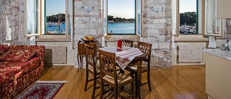 Una habitación con una mesa de comedor, sillas, un sofá y vistas al mar a través de amplios ventanales.