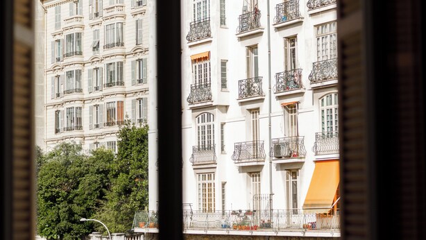 A multi-story building with balconies, a stone wall, and a clear sky. - Simple Stay - Fresh Start May 2026 (Nice)