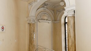 An interior hallway with ornate columns, a patterned floor, and a ceiling light fixture. - Simple Stay - Fresh Start May 2026 (Nice)