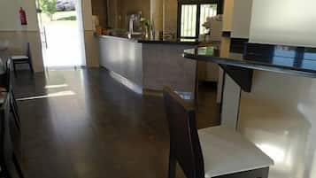 A modern kitchen with a central island, a dining area with a chair, and a view of the outdoors.