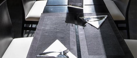 A dining area with a table set for two, a view of the parking area, and a balcony with a glass door.