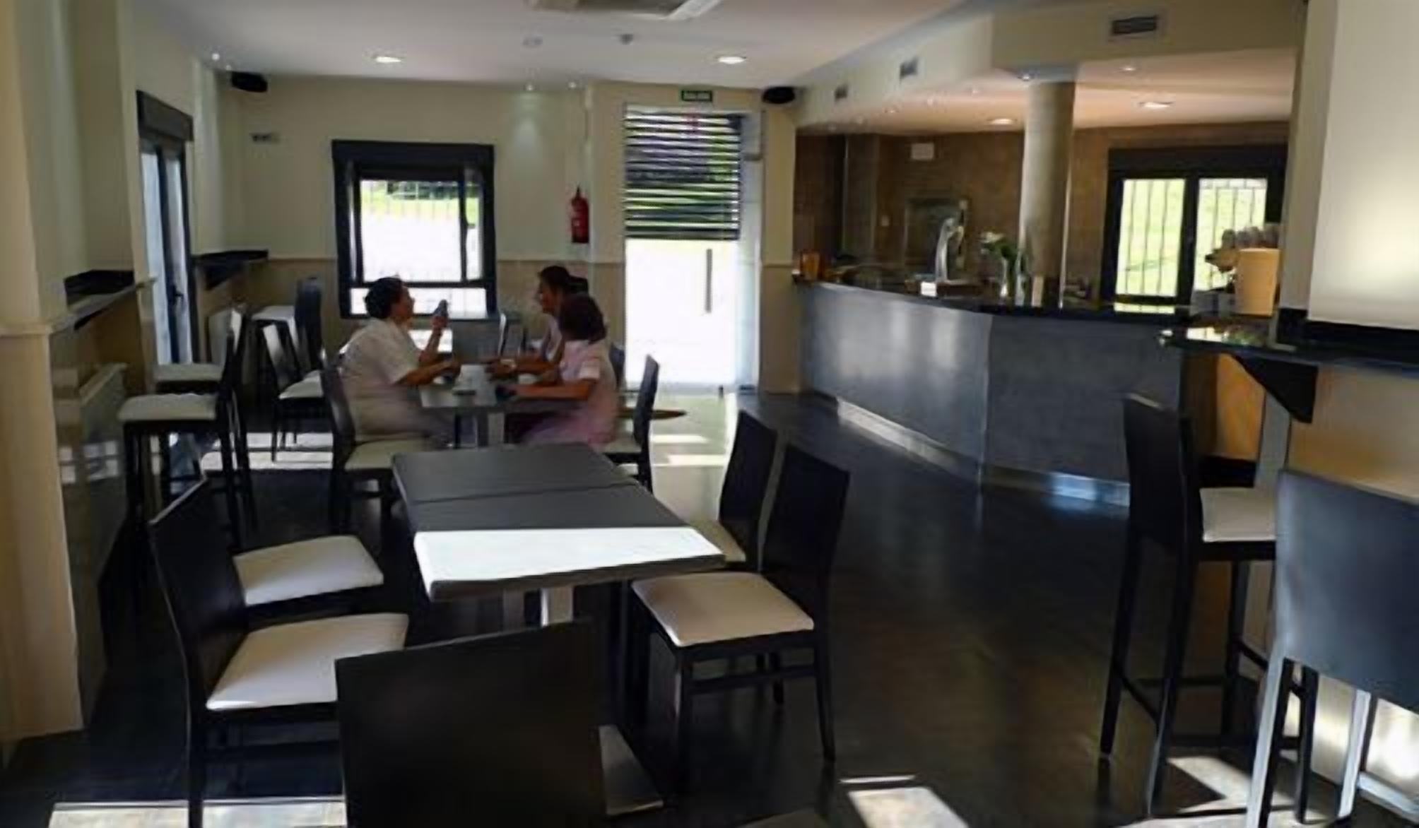 Un comedor moderno con mesas y sillas, una barra y vistas al exterior.