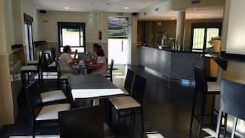 A modern dining area with tables and chairs, a counter, and a view of the outdoors.