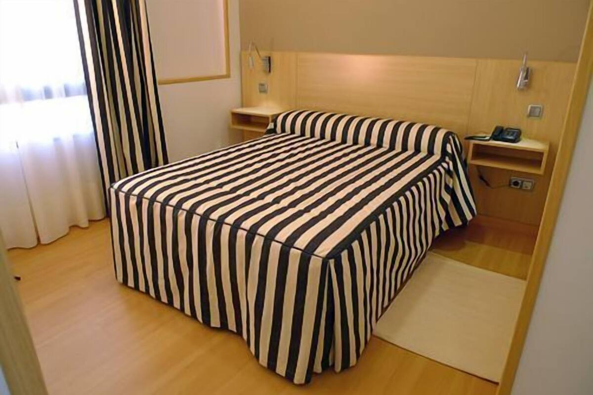 Une chambre d’hôtel avec un lit, une table de chevet et une petite table d’appoint.