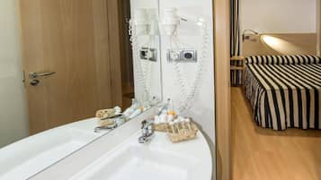 A modern bathroom with a large white sink, a hairdryer, and a mirror.