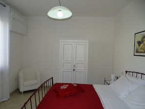 Une chambre à coucher comprenant un lit, une armoire, une chaise et une table de chevet.