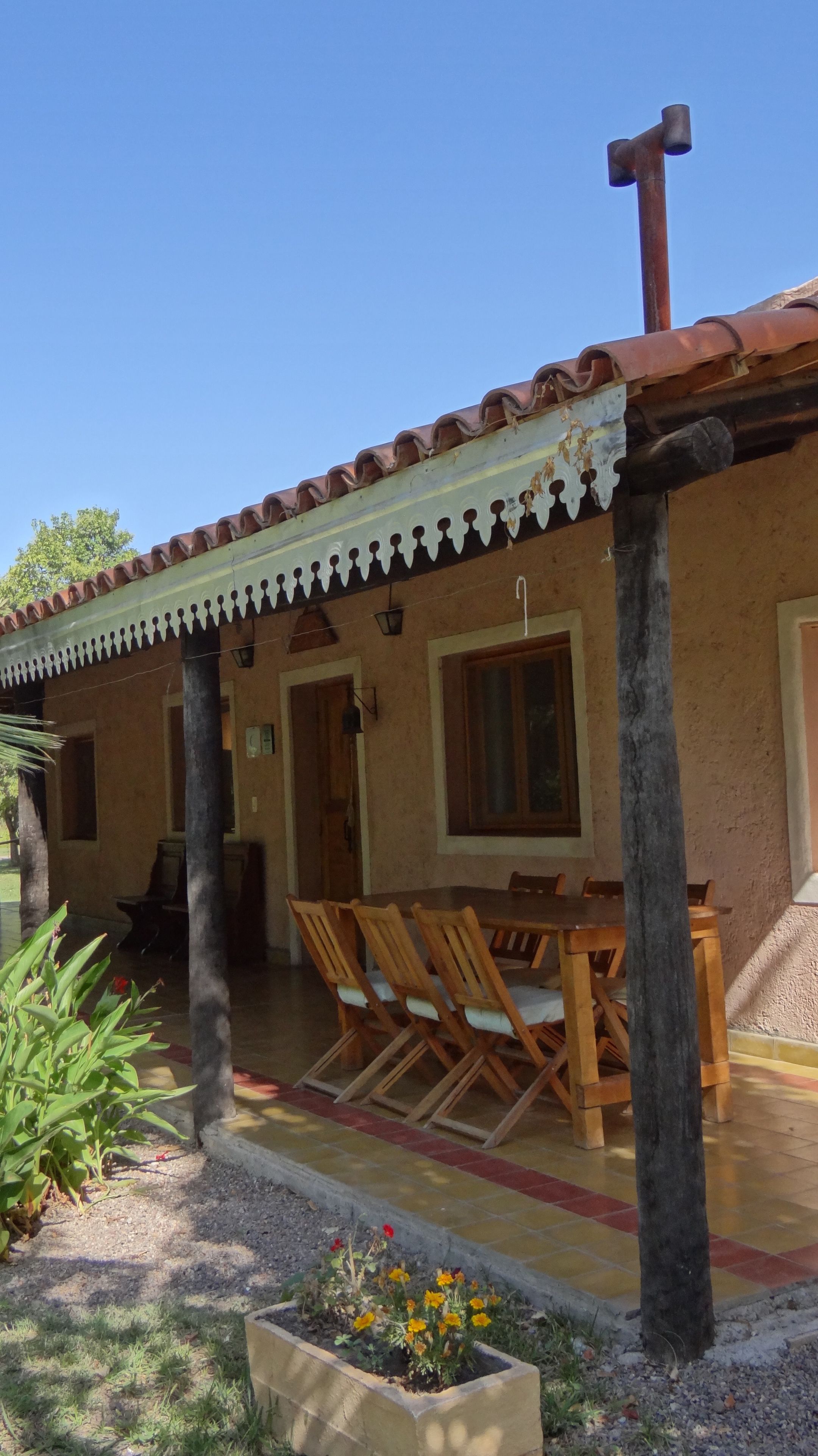 A building with a tiled roof, wooden furniture, and a garden area.