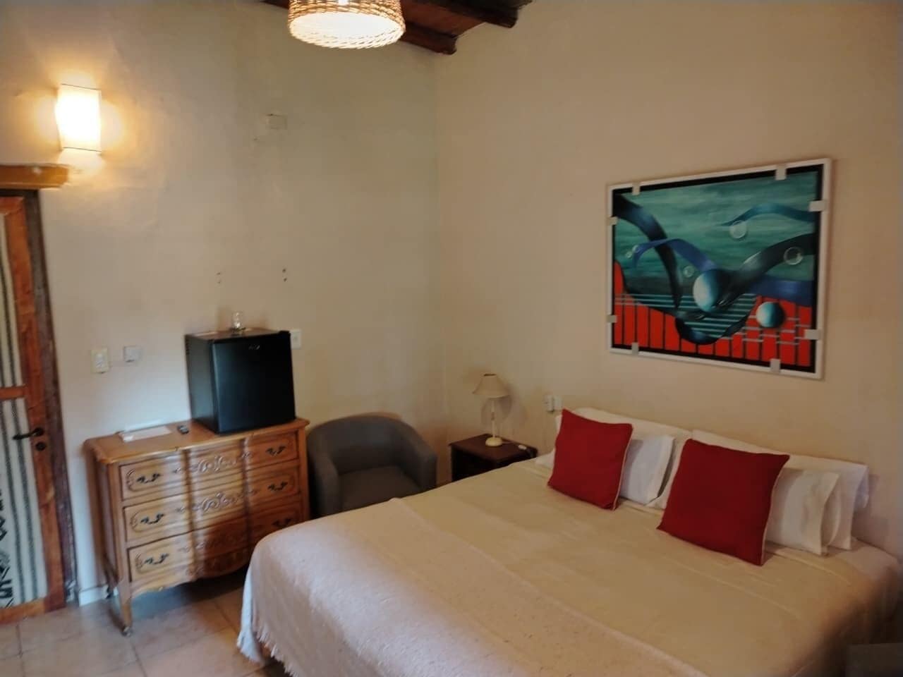 Une chambre à coucher avec un lit, une commode, une chaise, un bureau et un tableau accroché au mur.