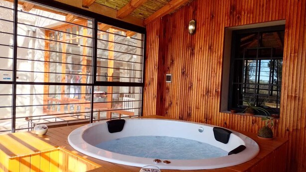 Una cabaña de madera con jacuzzi, ventanas amplias y una terraza de madera.