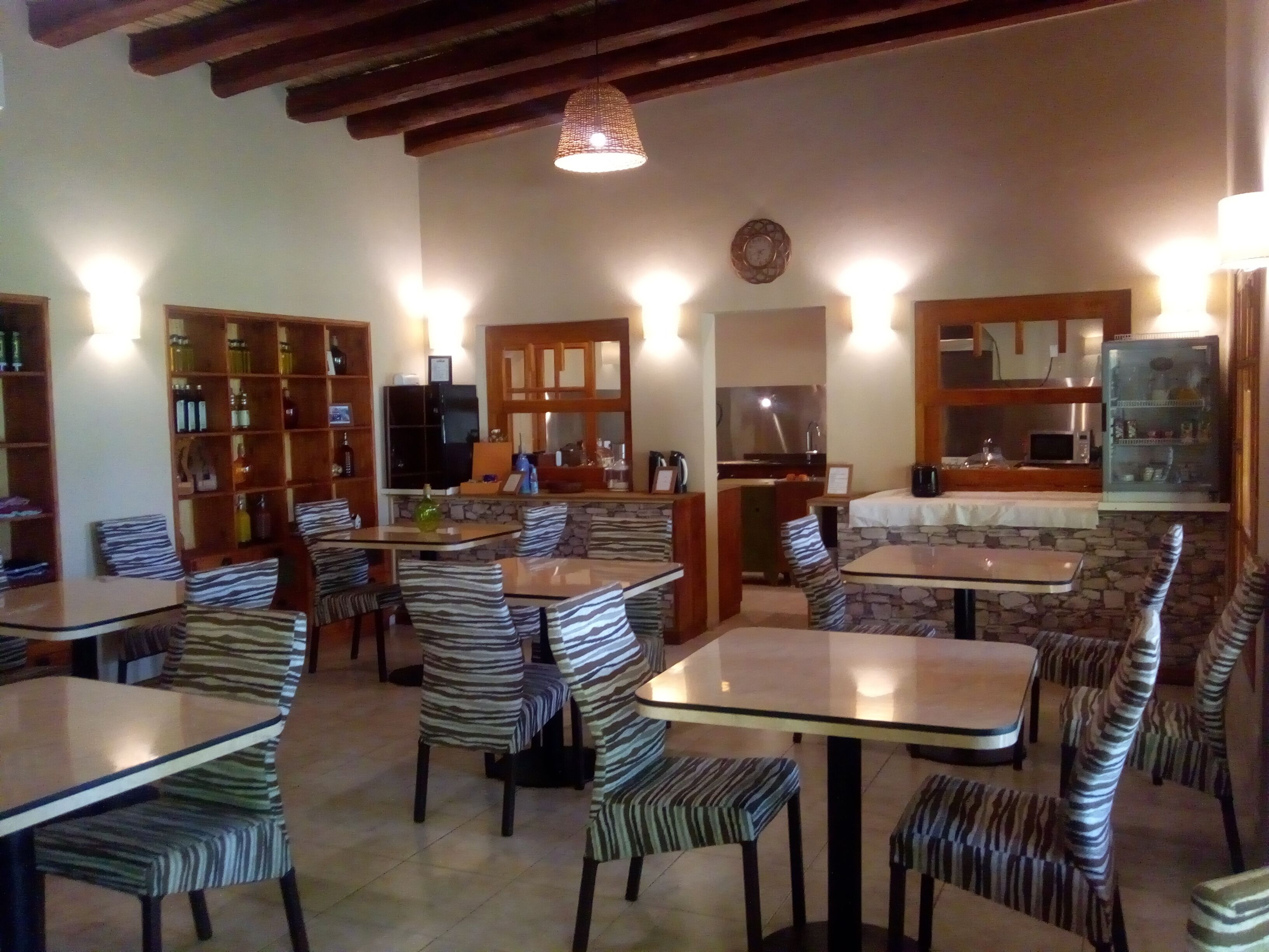 Un restaurante con varias mesas y sillas, una zona de cocina y una barra.