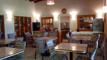 Un restaurante con varias mesas y sillas, una zona de cocina y una barra.