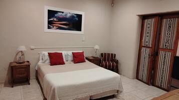A bedroom with a bed, two bedside tables, a chair, a wardrobe, and a painting on the wall.