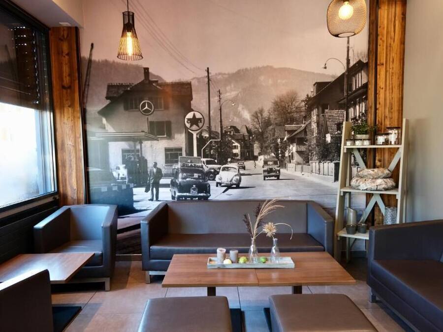 Un interior acogedor con asientos, una mesa con elementos decorativos y un mural de una escena callejera.