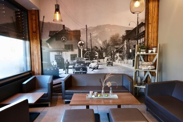 Un interior acogedor con asientos, una mesa con elementos decorativos y un mural de una escena callejera.