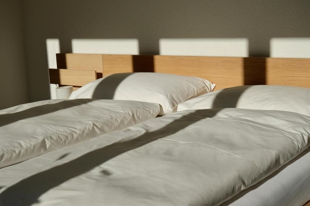 Ein Bett mit Holz Kopfteil und weißer Bettwäsche.