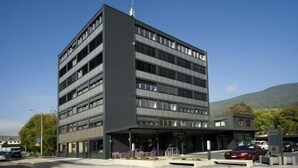 Um edifício moderno de vários andares com telhado plano e uma área de entrada destacada.