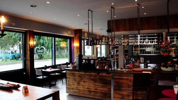 Uma área de bar moderna com balcão de madeira, assentos e vista para a rua.