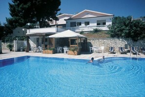 Una piscina al aire libre de temporada, sombrillas