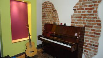 Una habitación con un piano y una guitarra frente a una pared de ladrillo.