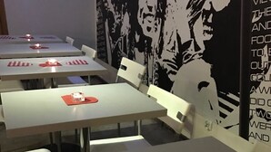 A dining area with tables set for two, each with a red and white checkered placemat and a candle. - La Guitarra Hostel (Gdansk)