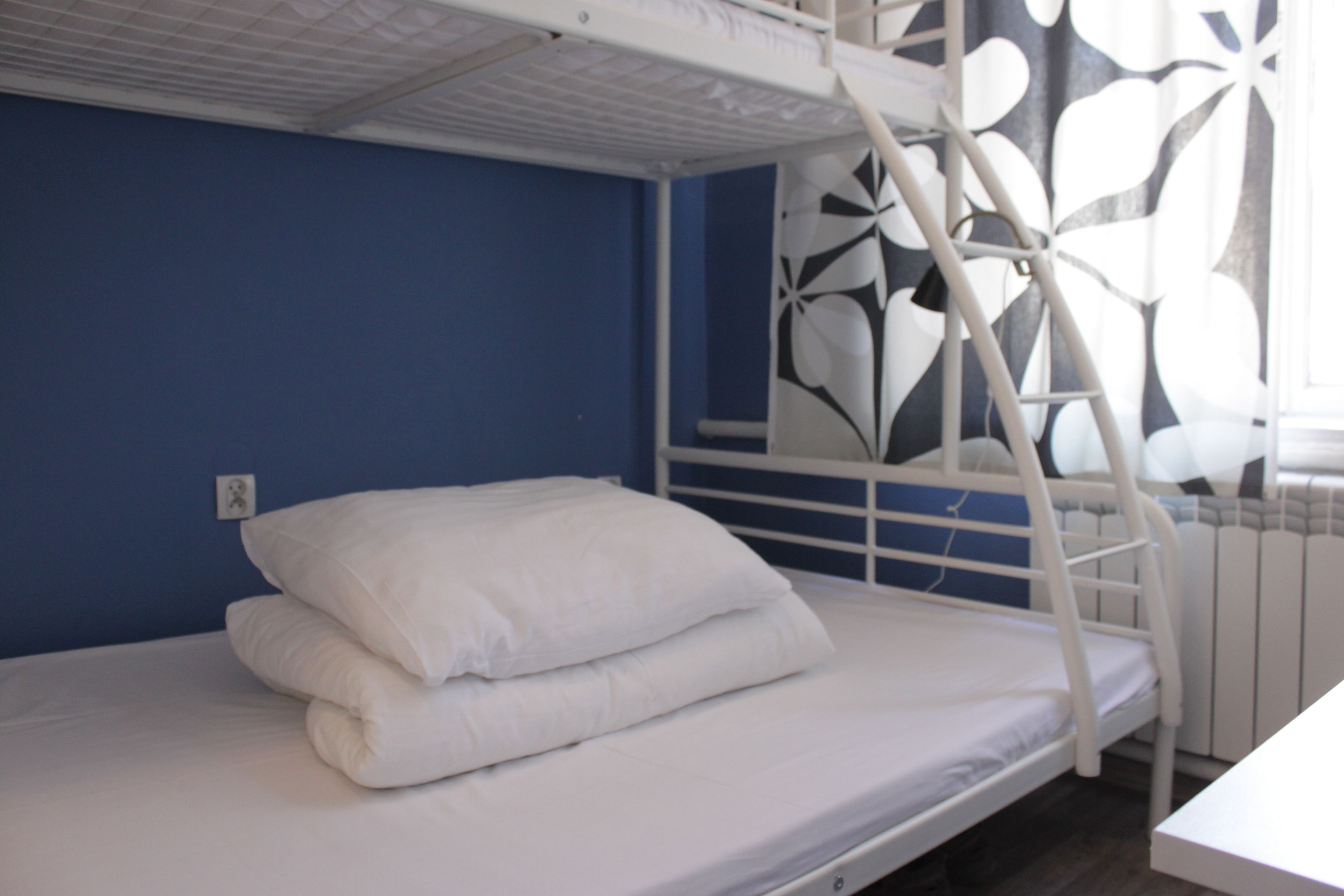 Ein Stockbett mit weißer Bettwäsche und einem weißen Metallgestell.