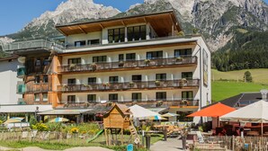 Un hôtel à plusieurs étages doté de balcons, d’un espace extérieur aménagé et offrant une vue sur les montagnes.