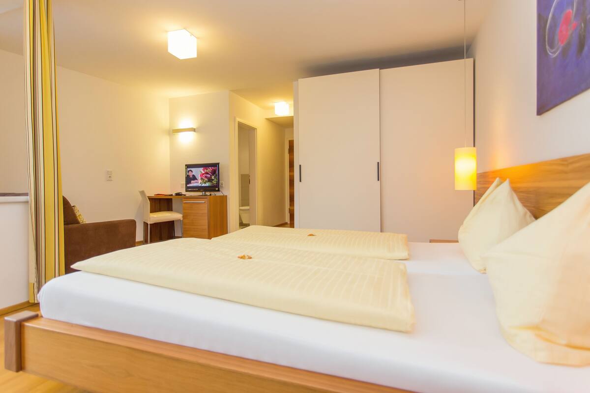 Una habitación de hotel con una cama, un escritorio, una silla y un armario.