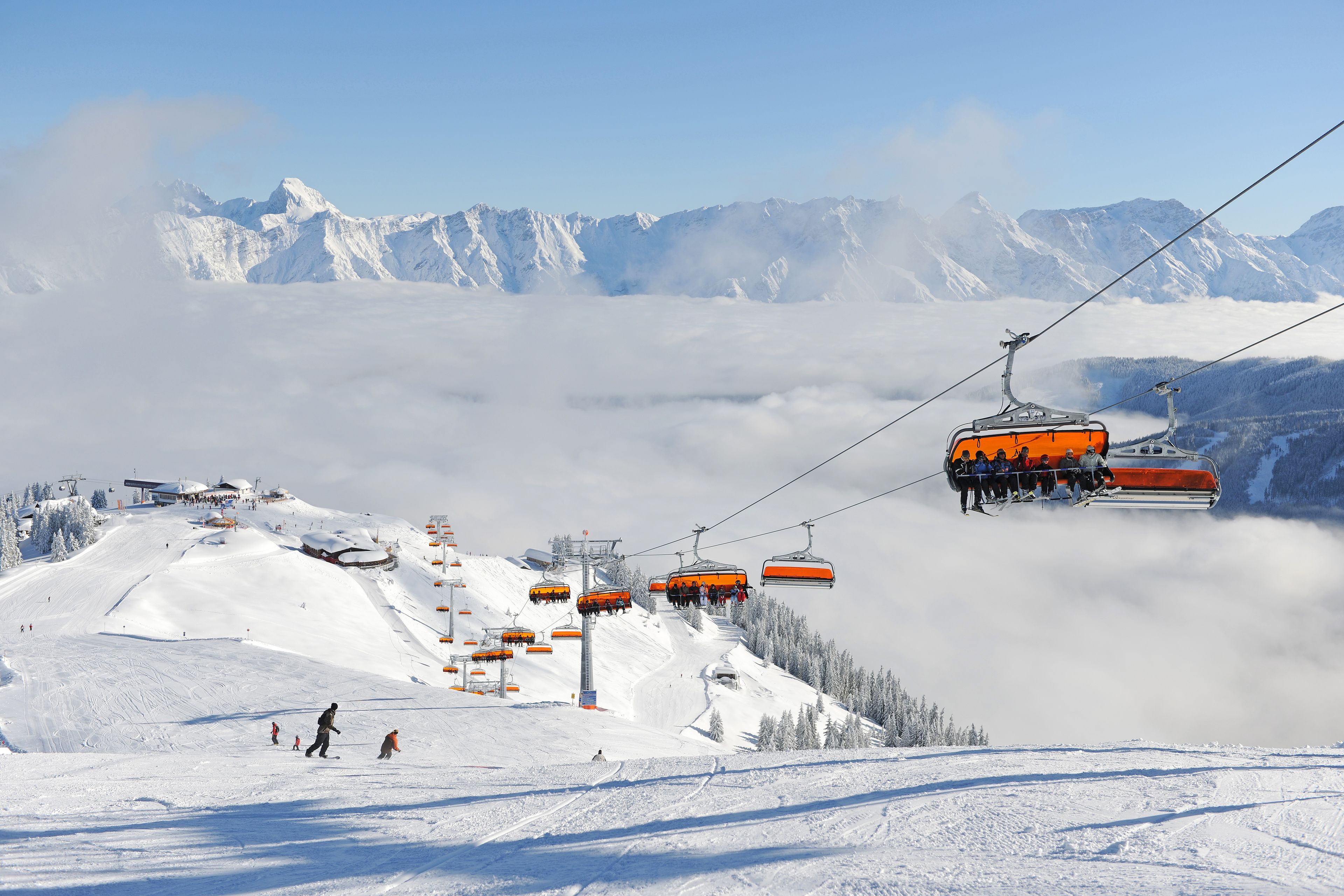 A ski lift with passengers, a snowy mountain slope, and a clear sky.