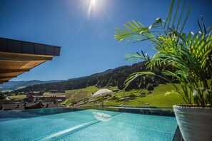 En pool med utsikt över ett bergigt landskap och en byggnad i bakgrunden.