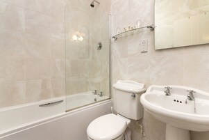 A modern bathroom with a glass-enclosed shower, a toilet, and a sink.