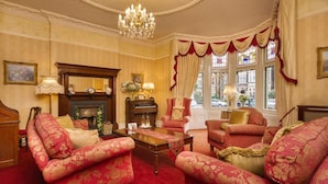A traditional room with a fireplace, red upholstered furniture, and a chandelier. - Lincoln House Hotel (Cardiff)