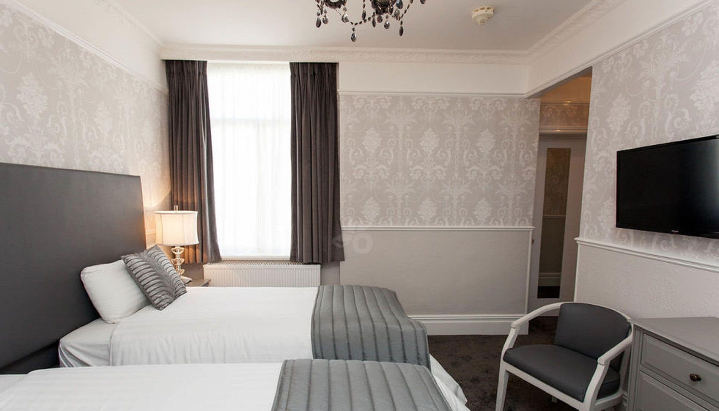A hotel room with two beds, a TV, a chair, and a dresser.